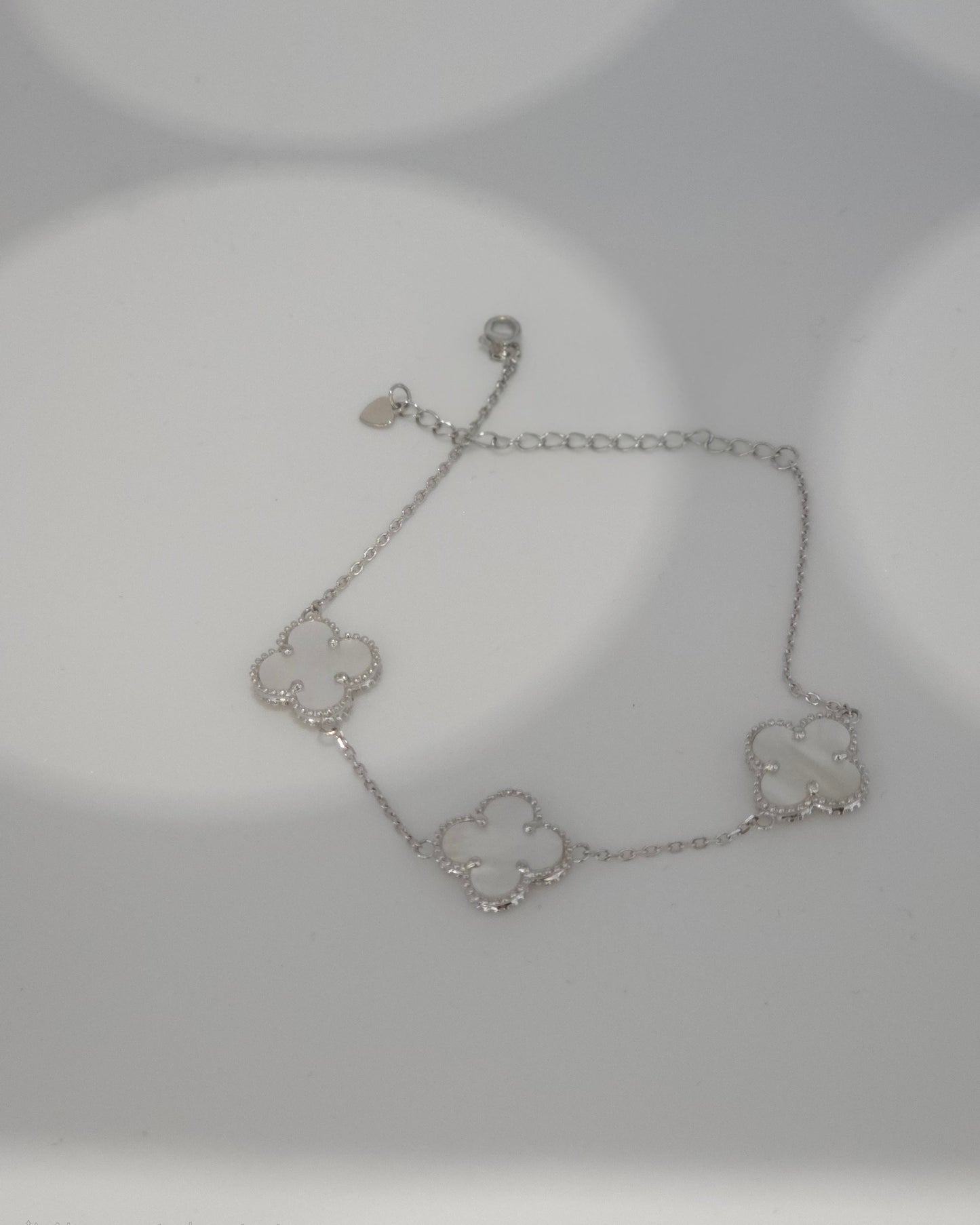 Silver bracelet with clover designs on a light gray background