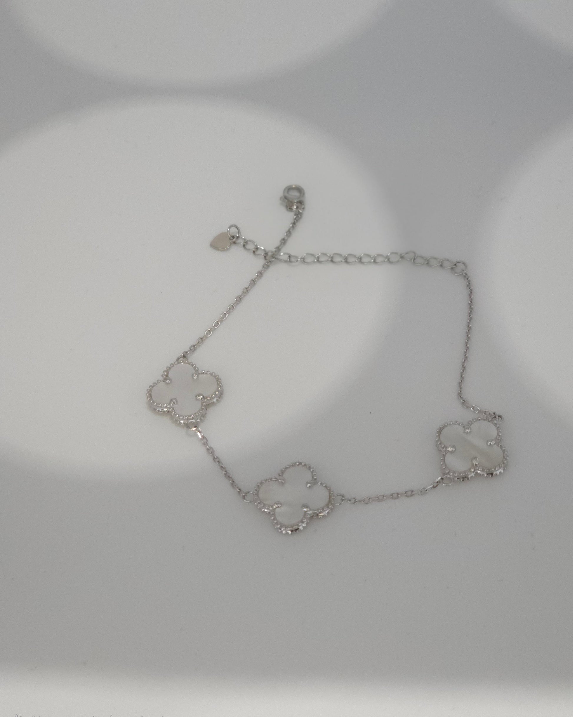 Silver bracelet with clover designs on a light gray background