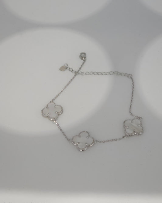 Silver bracelet with clover designs on a light gray background