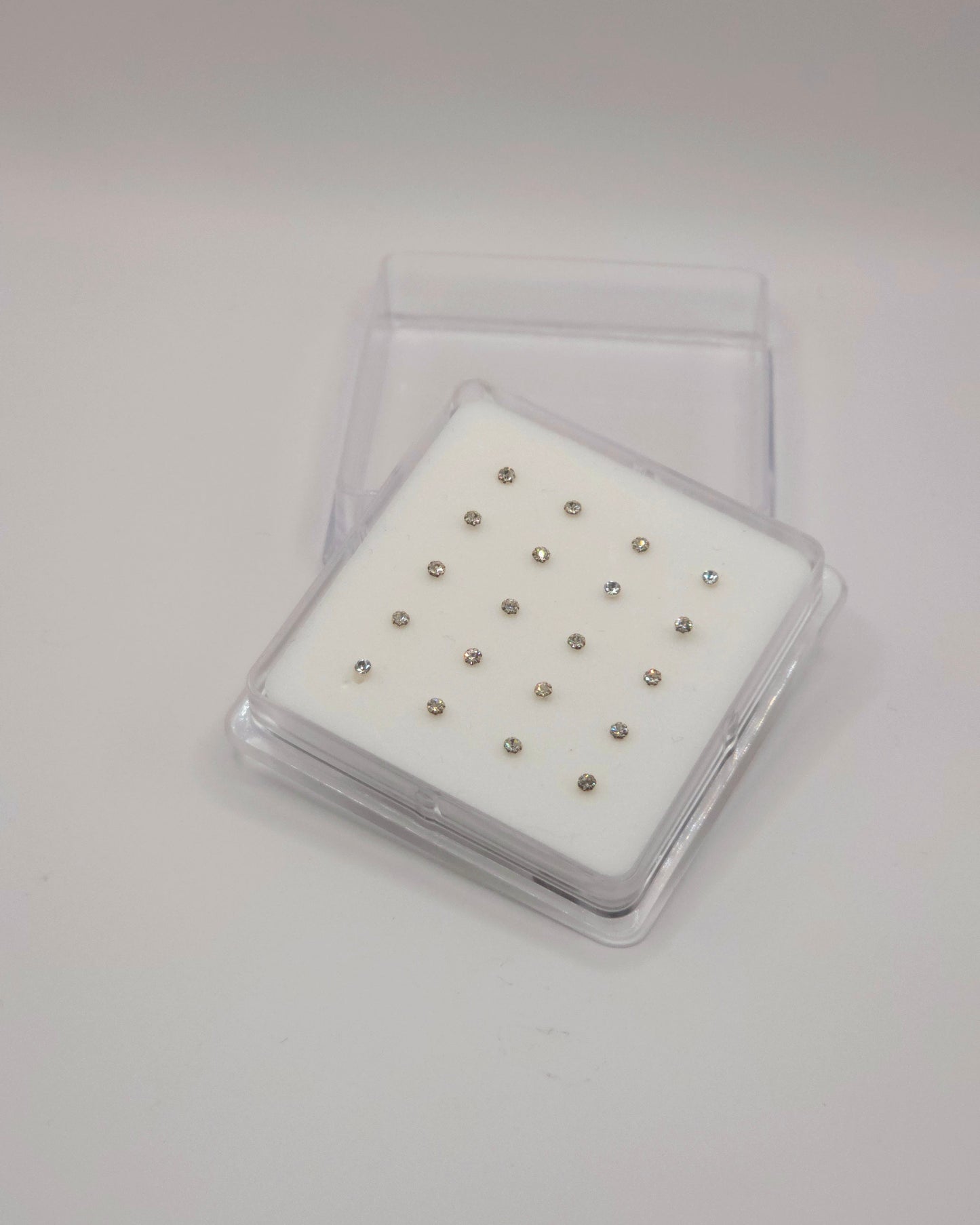 Set of small metal studs in a clear plastic case on a white background