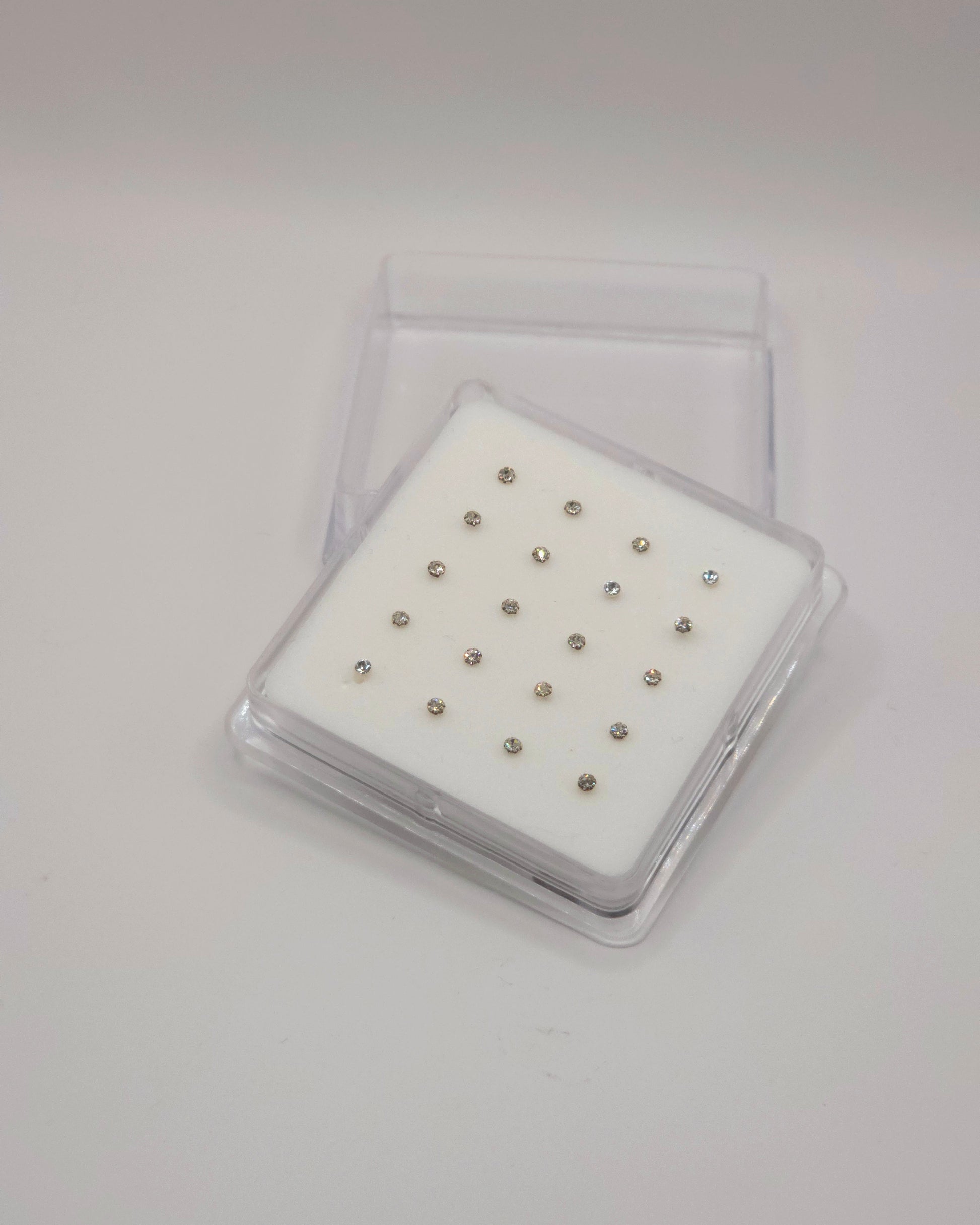 Set of small metal studs in a clear plastic case on a white background
